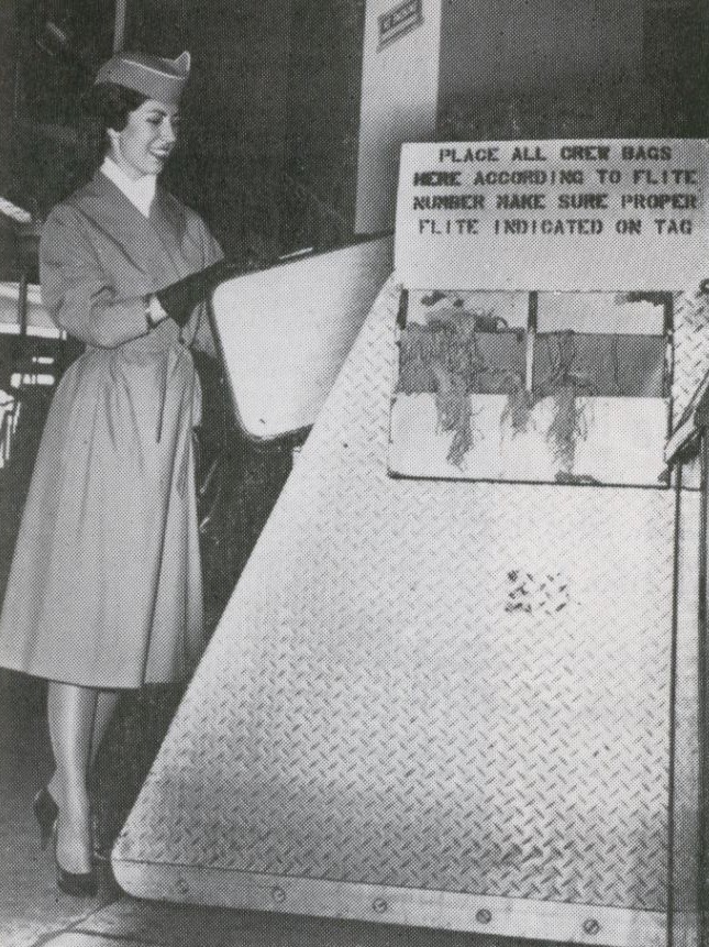 1959 A Pan Am stewardess tags her own suitcase on the ramp at New York JFK airport.